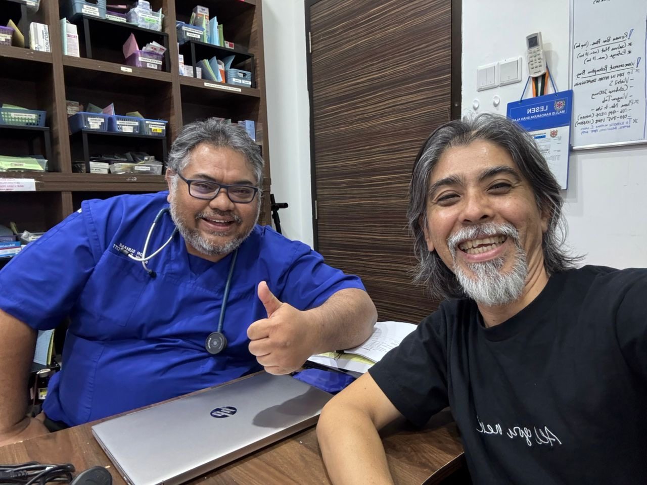 Two partner doctors sharing a thumbs up at the clinic desk.
