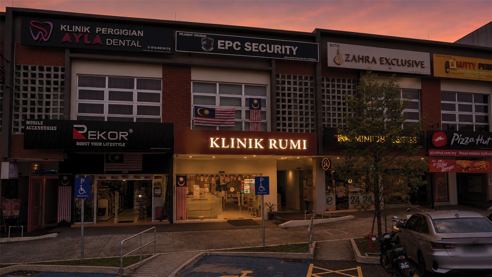 Klinik Rumi signage lit at night on a neighbourhood shoplot.